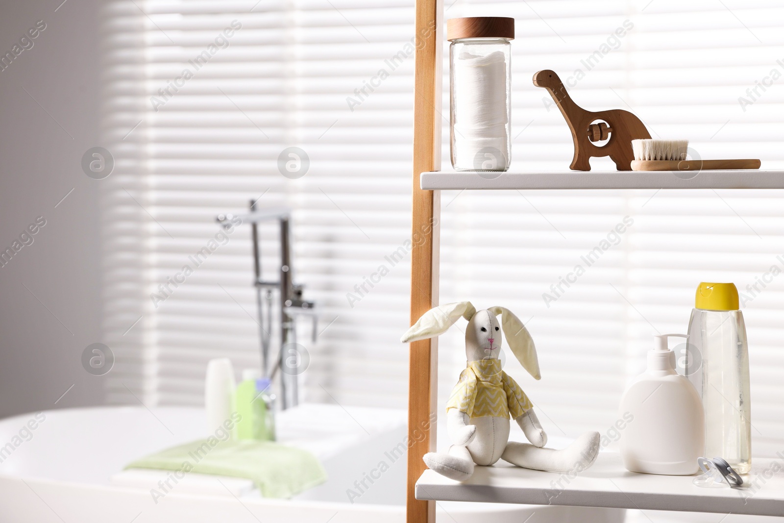 Photo of Baby accessories and bathing products on rack in bathroom. Space for text