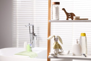 Photo of Baby accessories and bathing products on rack in bathroom. Space for text