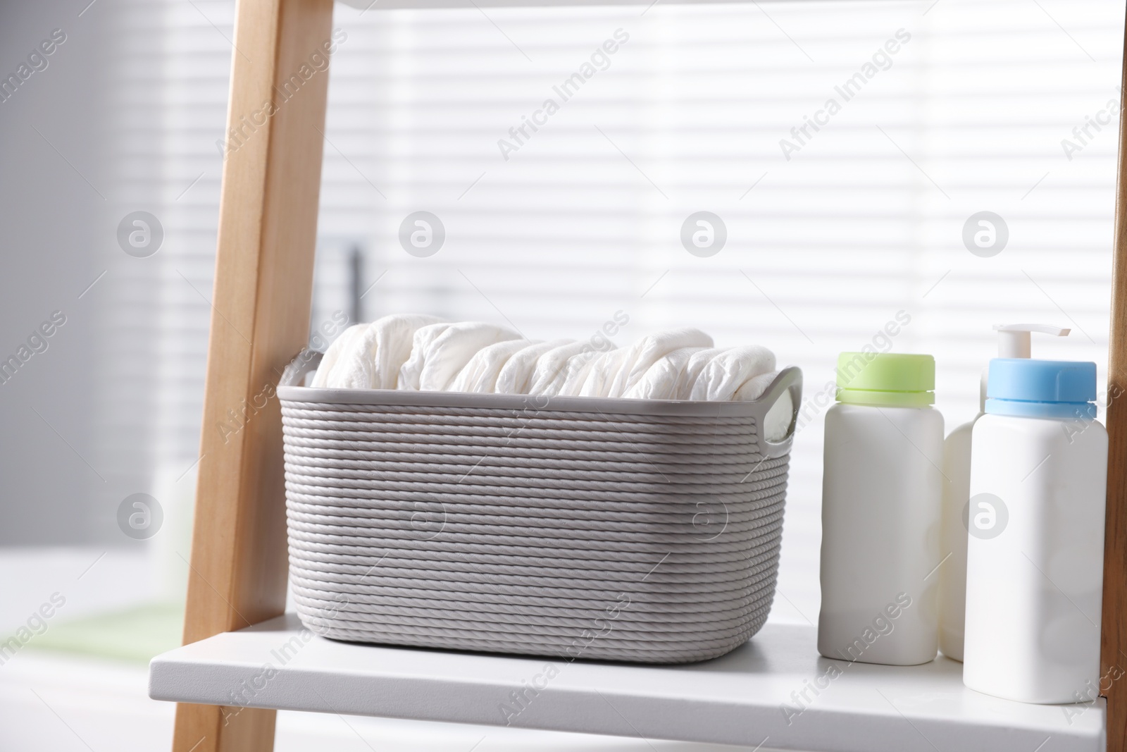 Baby bathing products and diapers on rack in bathroom, closeup Photo of Baby bathing products and diapers on rack in bathroom, closeup