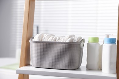 Photo of Baby bathing products and diapers on rack in bathroom, closeup