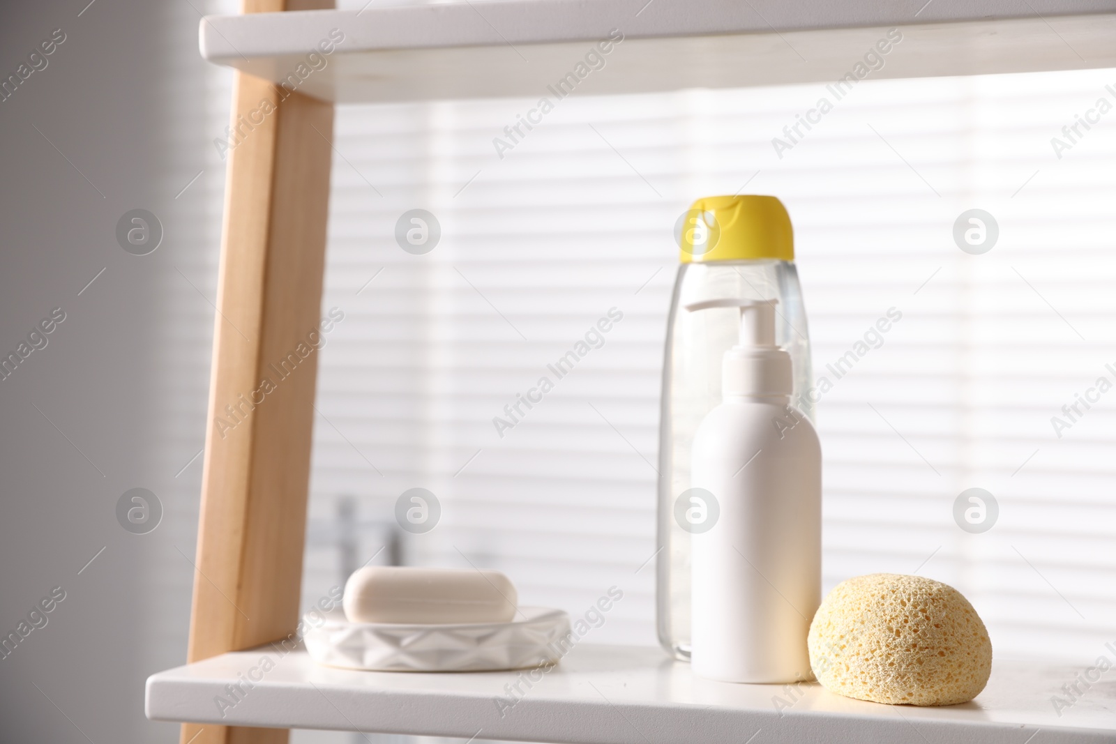 Photo of Baby bathing products and loofah on rack in bathroom, closeup