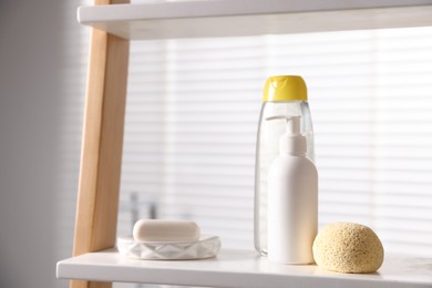 Photo of Baby bathing products and loofah on rack in bathroom, closeup