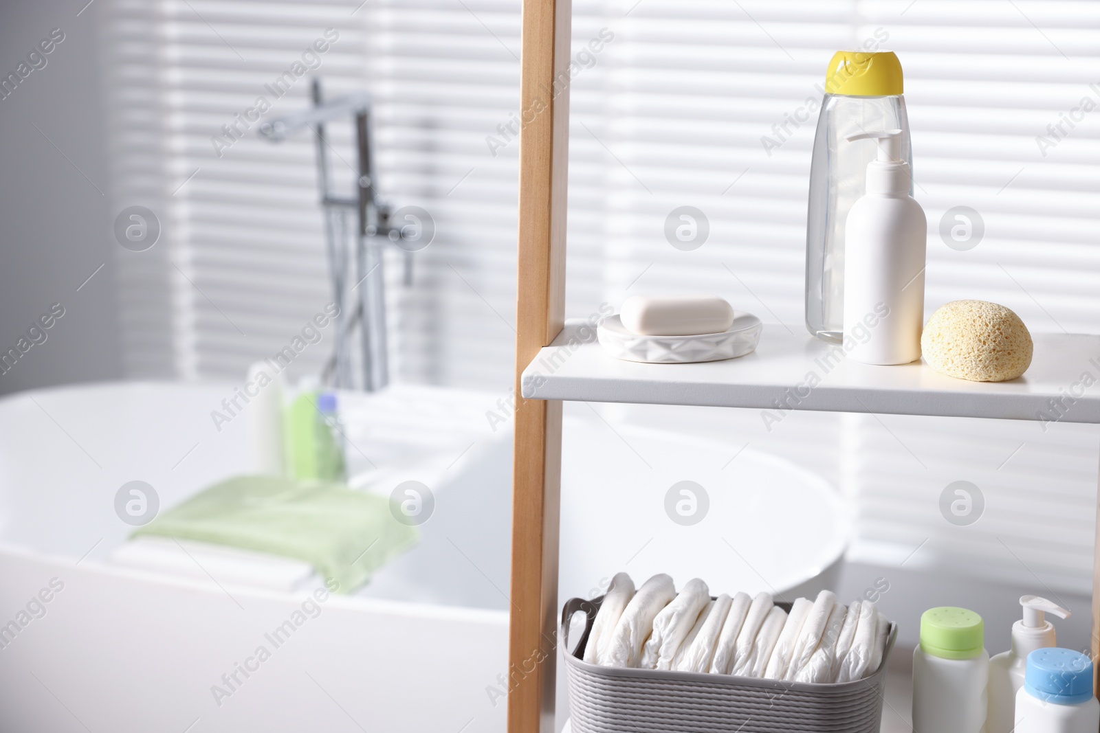 Photo of Baby bathing products and diapers on rack in bathroom, closeup