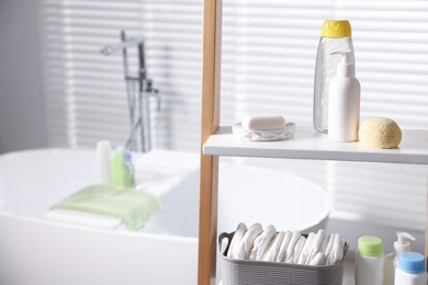 Photo of Baby bathing products and diapers on rack in bathroom, closeup