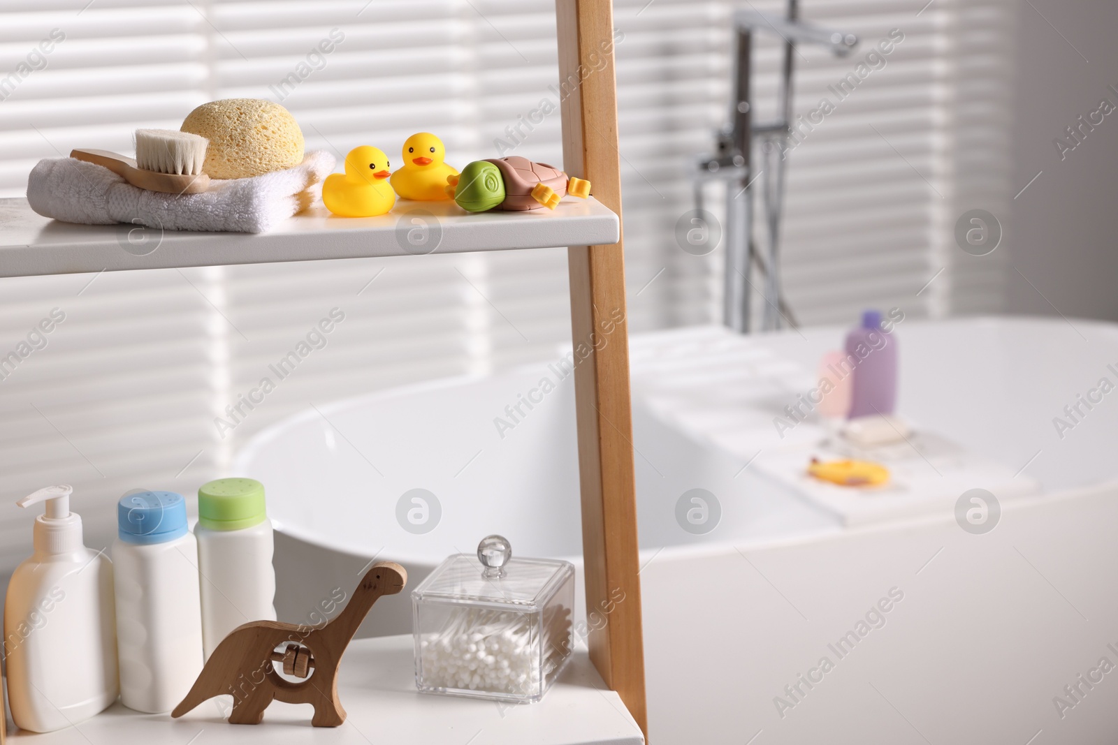 Photo of Baby bath accessories and care products on rack in bathroom, closeup