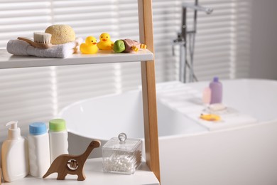 Photo of Baby bath accessories and care products on rack in bathroom, closeup