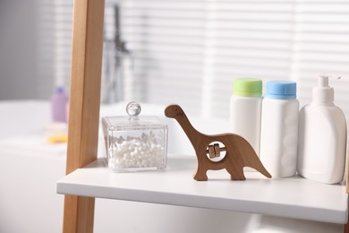 Photo of Baby bath accessories and care products on rack in bathroom, closeup