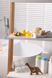 Photo of Baby bath accessories and care products on rack in bathroom, closeup