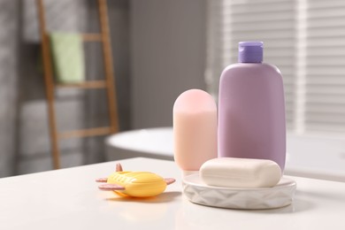 Photo of Baby accessories and bathing products on white table in bathroom. Space for text
