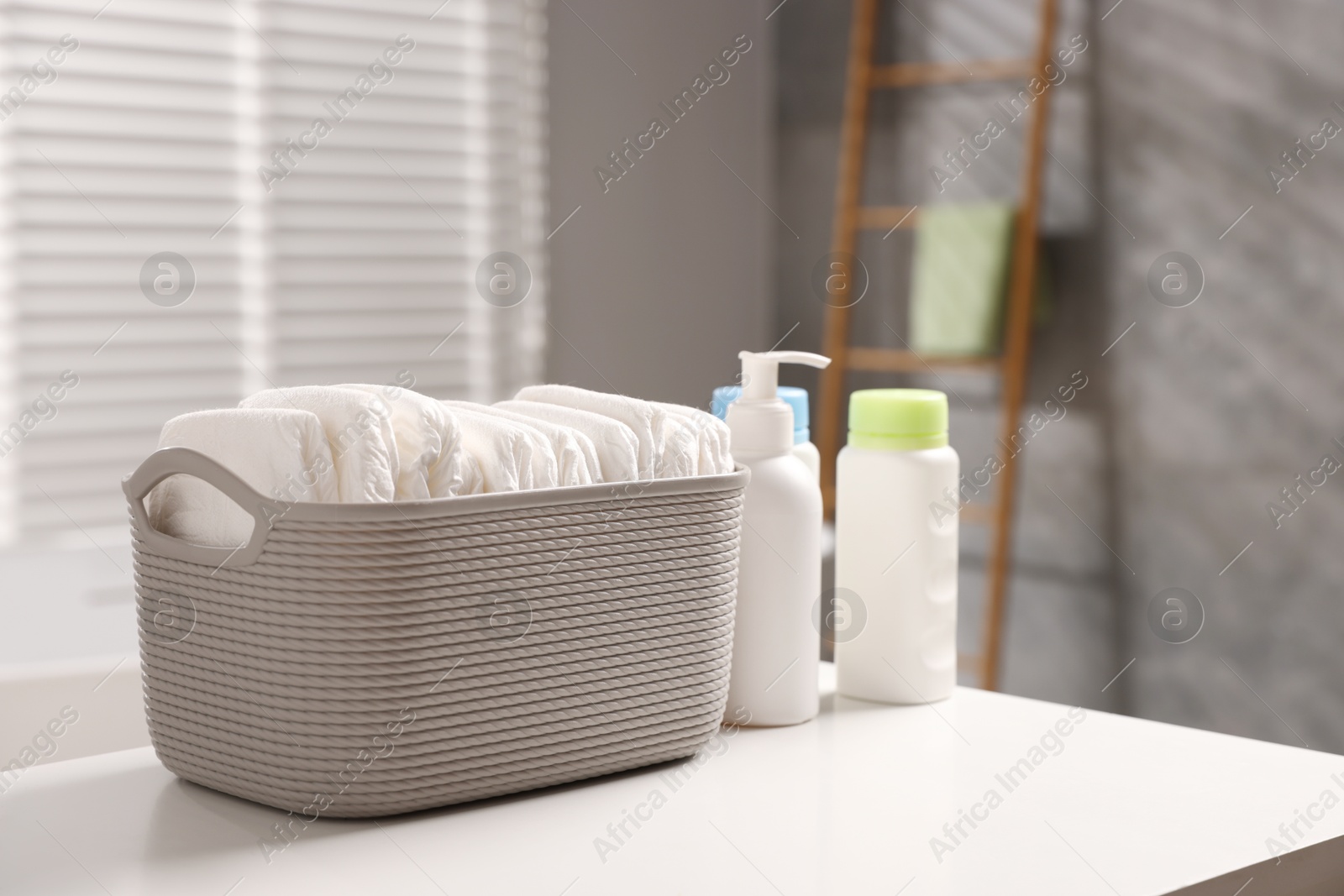 Photo of Baby bathing products and diapers on white table in bathroom