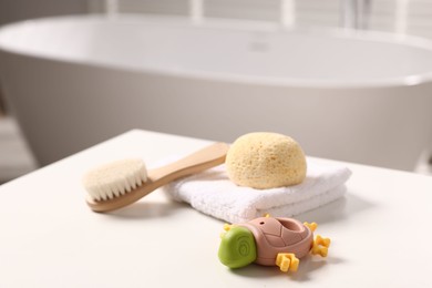 Photo of Baby bath accessories on white table in bathroom, closeup