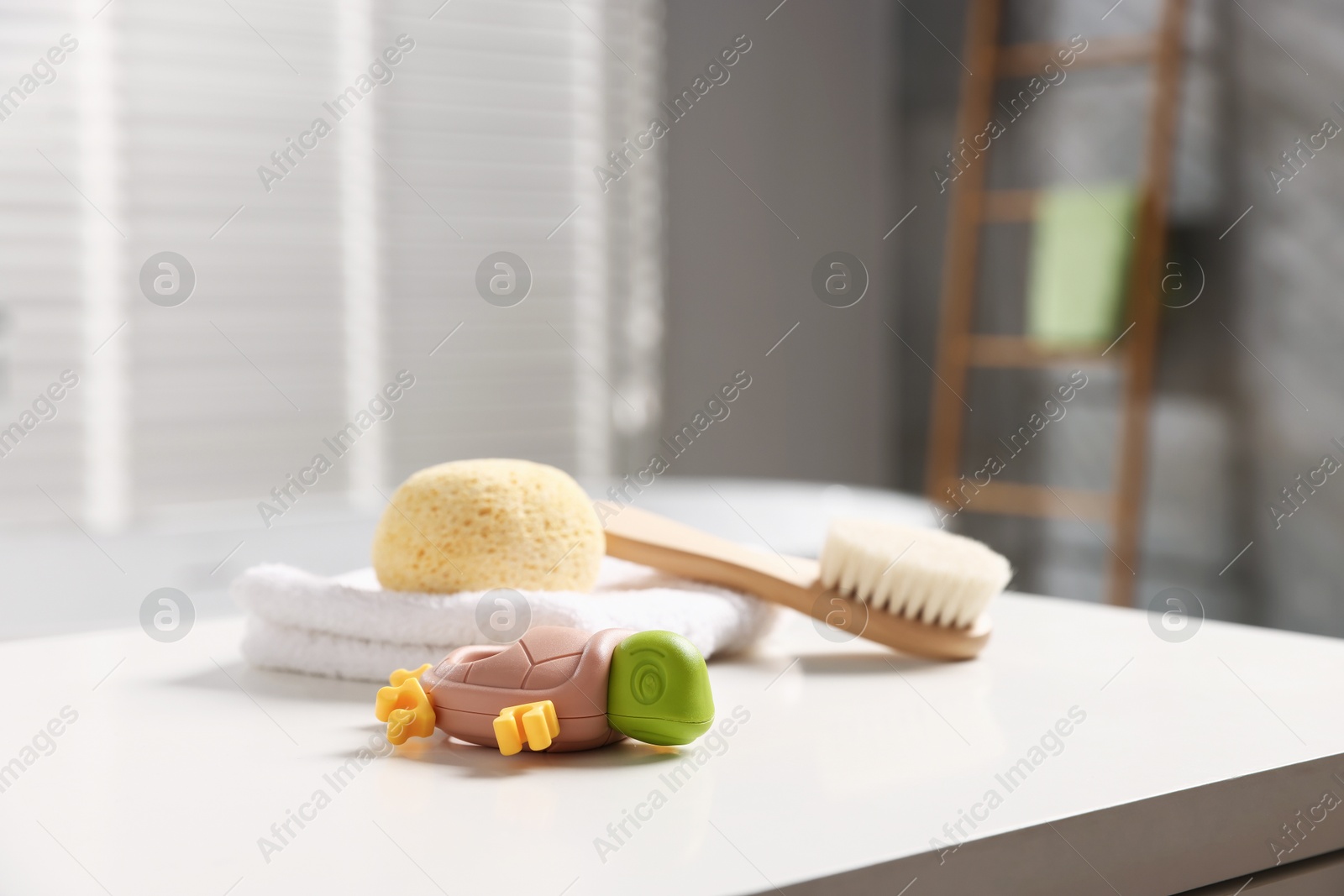 Photo of Baby bath accessories on white table in bathroom, closeup
