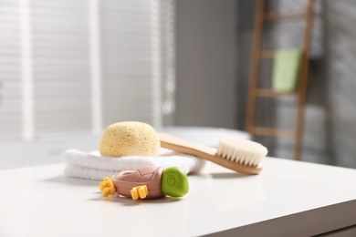 Photo of Baby bath accessories on white table in bathroom, closeup