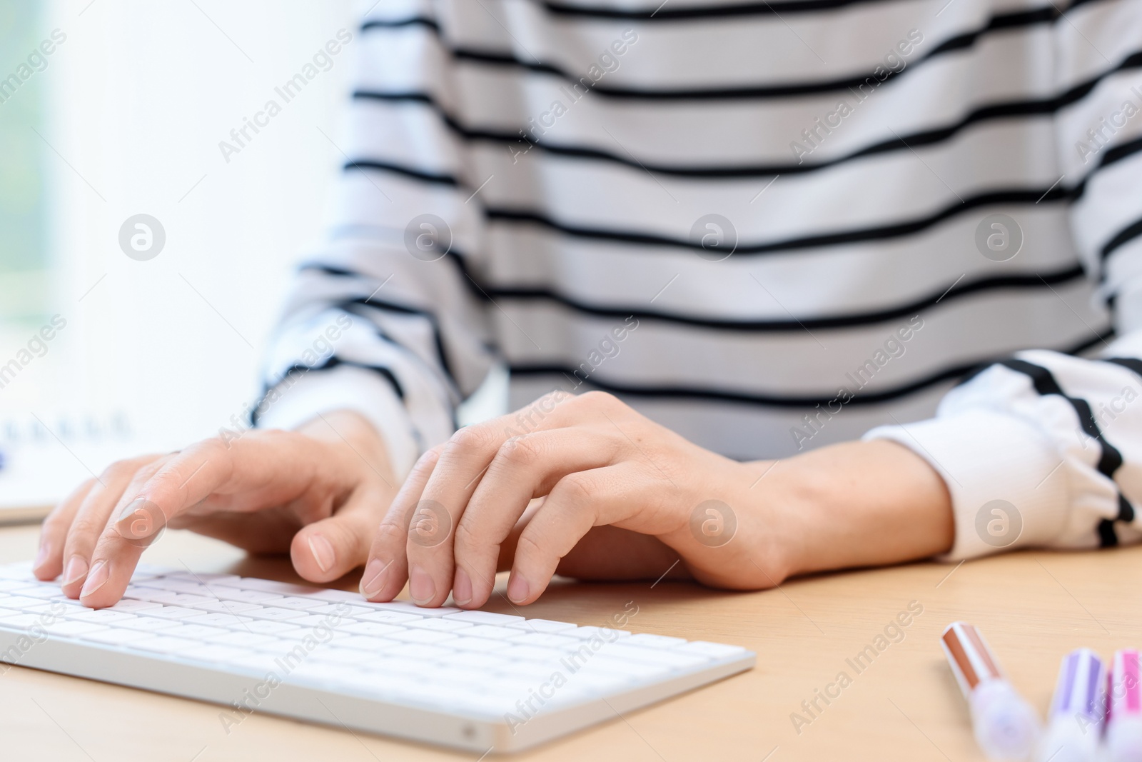 Photo of Woman using computer at wooden desk indoors, closeup. Home workplace