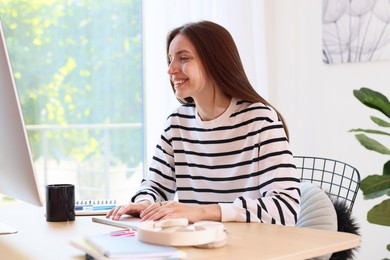 Photo of Woman using computer at wooden desk indoors. Home workplace