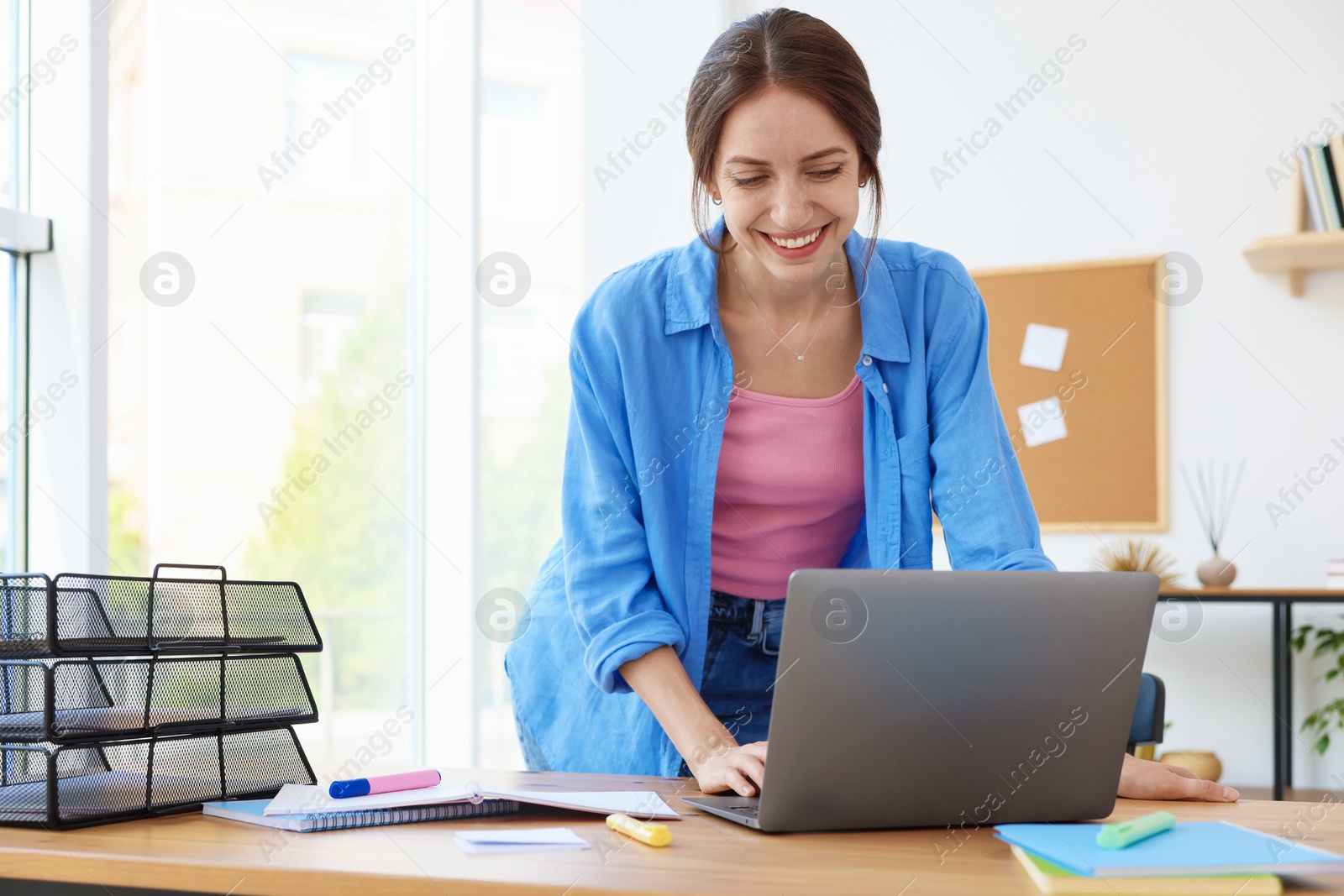 Photo of Woman using laptop at wooden desk indoors. Home workplace