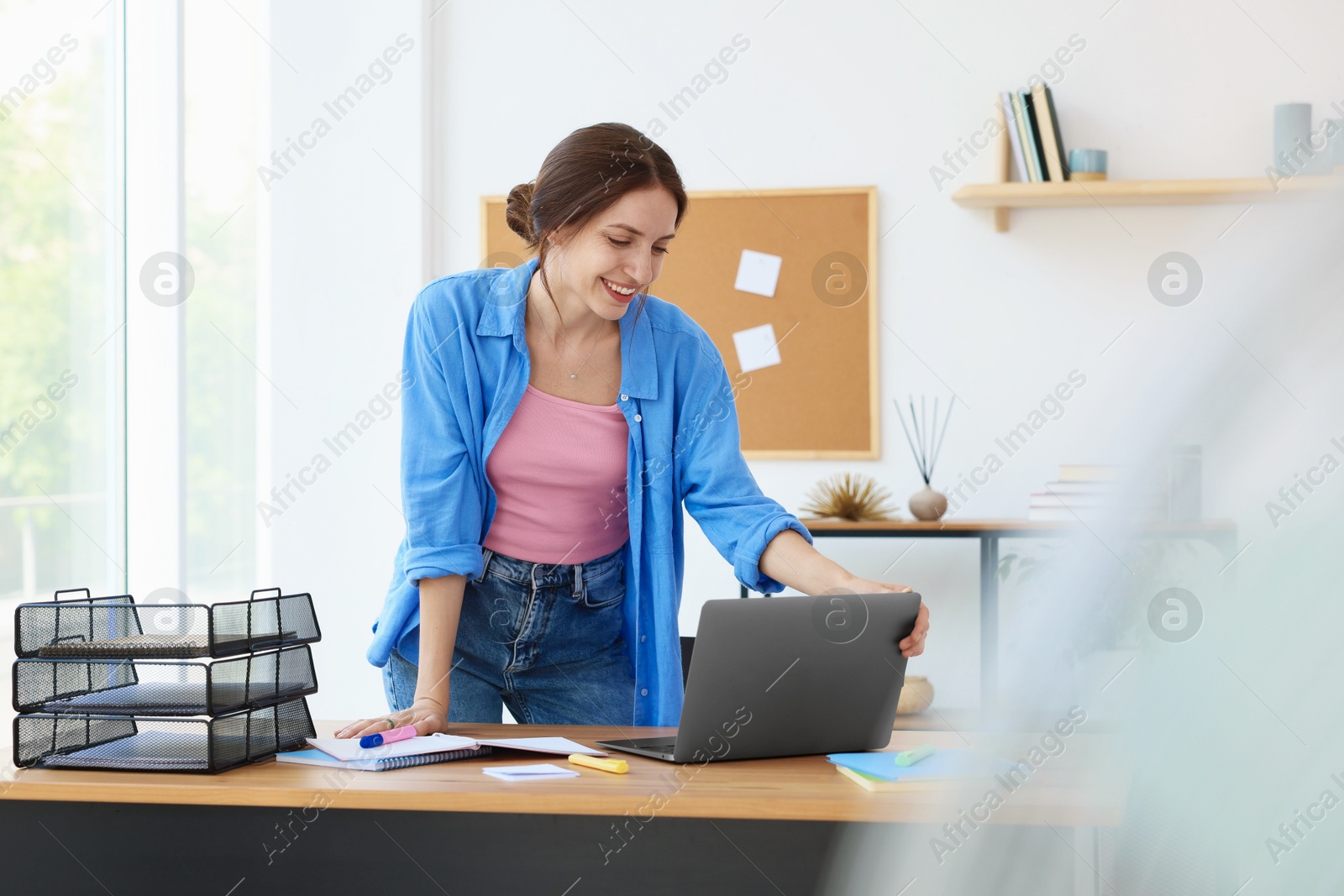 Photo of Woman using laptop at wooden desk indoors. Home workplace