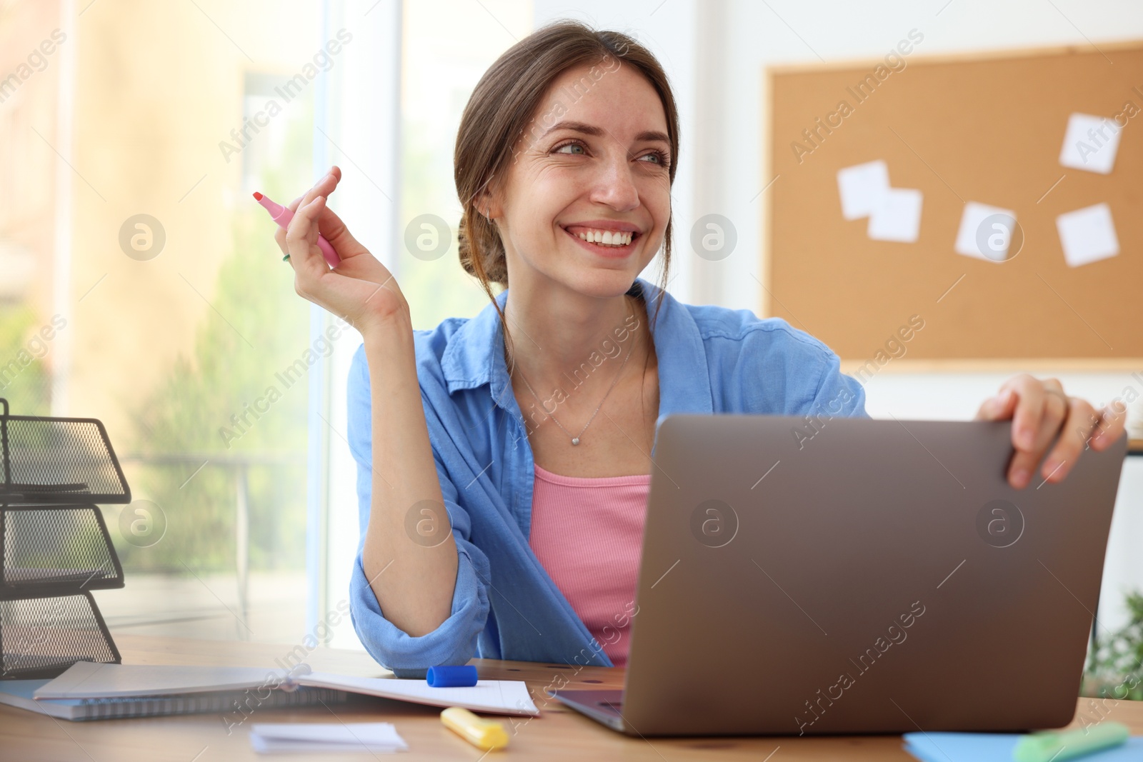 Photo of Woman using laptop at wooden desk indoors. Home workplace