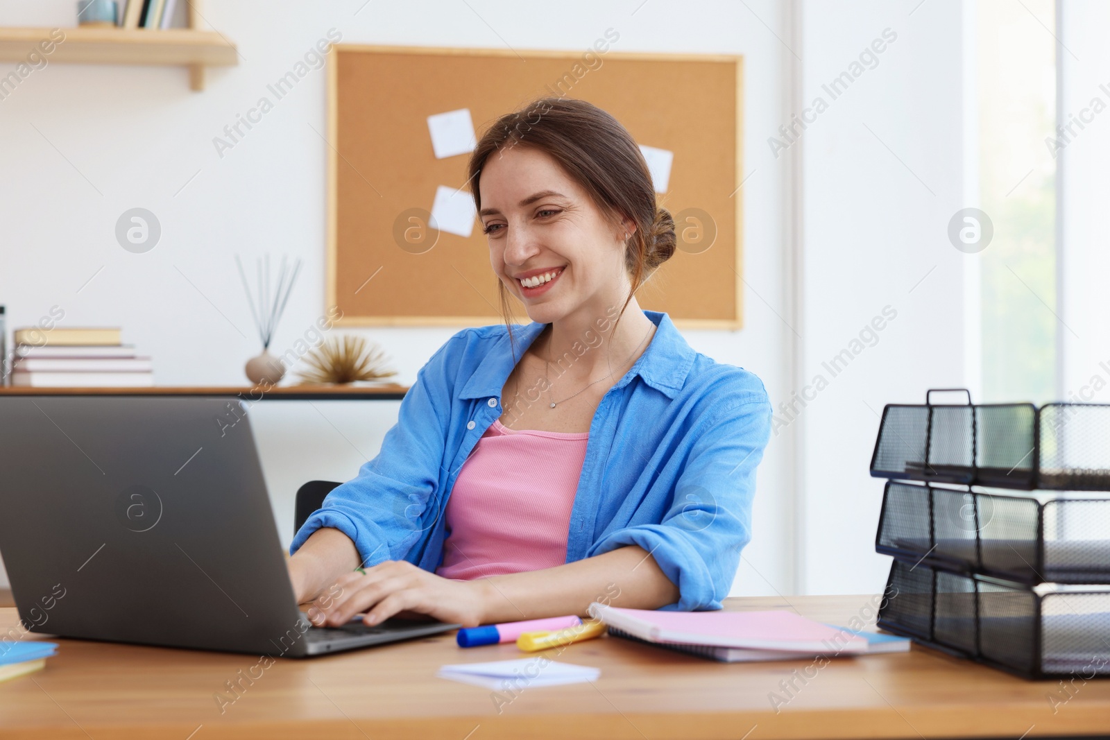 Photo of Woman using laptop at wooden desk indoors. Home workplace