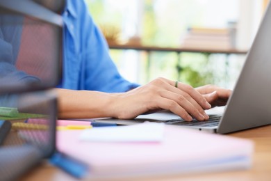Photo of Woman using laptop at wooden desk indoors, closeup. Home workplace