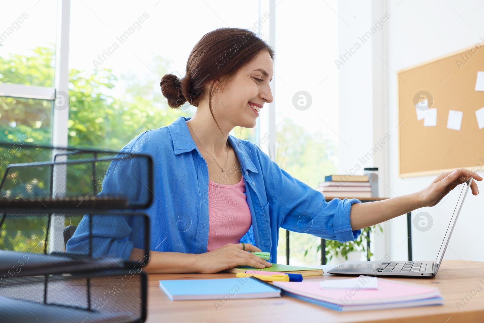 Photo of Woman using laptop at wooden desk indoors. Home workplace