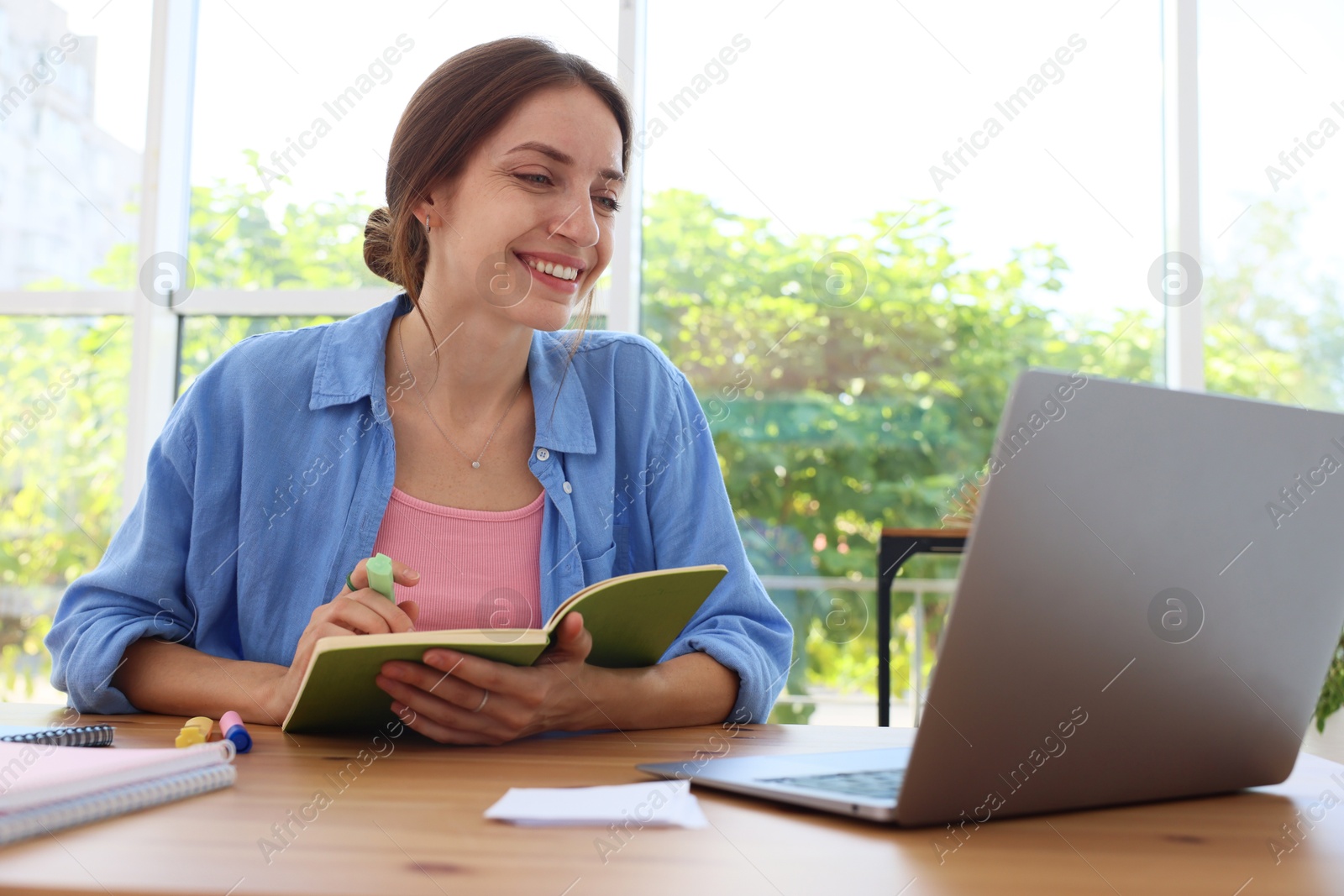 Photo of Woman using laptop at wooden desk indoors. Home workplace