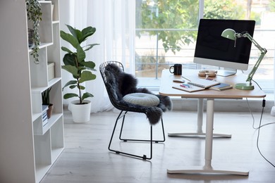 Photo of Home workspace. Modern computer, houseplant and stationery on wooden desk indoors