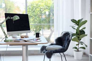 Photo of Home workspace. Modern computer, houseplant and stationery on wooden desk indoors