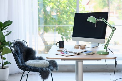 Photo of Home workspace. Modern computer, houseplant and stationery on wooden desk indoors
