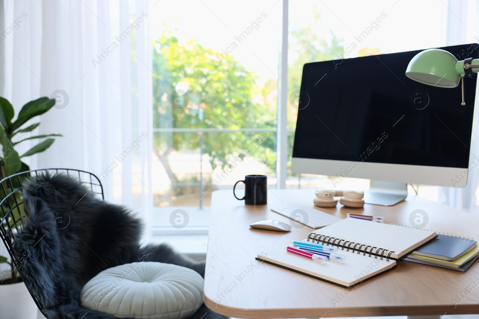 Photo of Home workspace. Modern computer, houseplant and stationery on wooden desk indoors