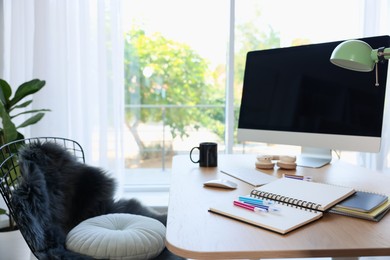 Photo of Home workspace. Modern computer, houseplant and stationery on wooden desk indoors
