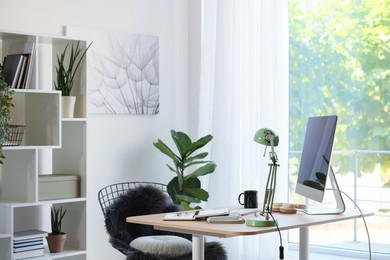 Photo of Home workspace. Modern computer, houseplant and stationery on wooden desk indoors