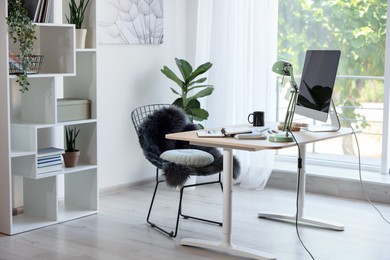 Photo of Home workspace. Modern computer, houseplant and stationery on wooden desk indoors