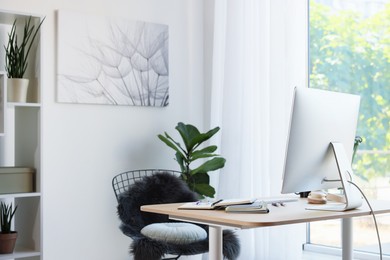 Photo of Home workspace. Modern computer, houseplant and stationery on wooden desk indoors