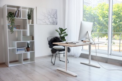 Photo of Home workspace. Modern computer, houseplant and stationery on wooden desk indoors