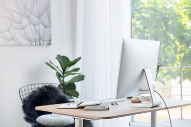 Photo of Home workspace. Modern computer, houseplant and stationery on wooden desk indoors