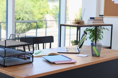 Photo of Home workspace. Modern laptop and stationery on wooden desk indoors