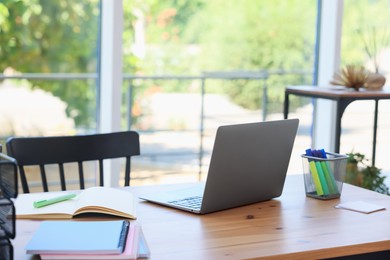 Photo of Home workspace. Modern laptop and stationery on wooden desk indoors