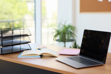 Photo of Home workspace. Modern laptop and stationery on wooden desk indoors