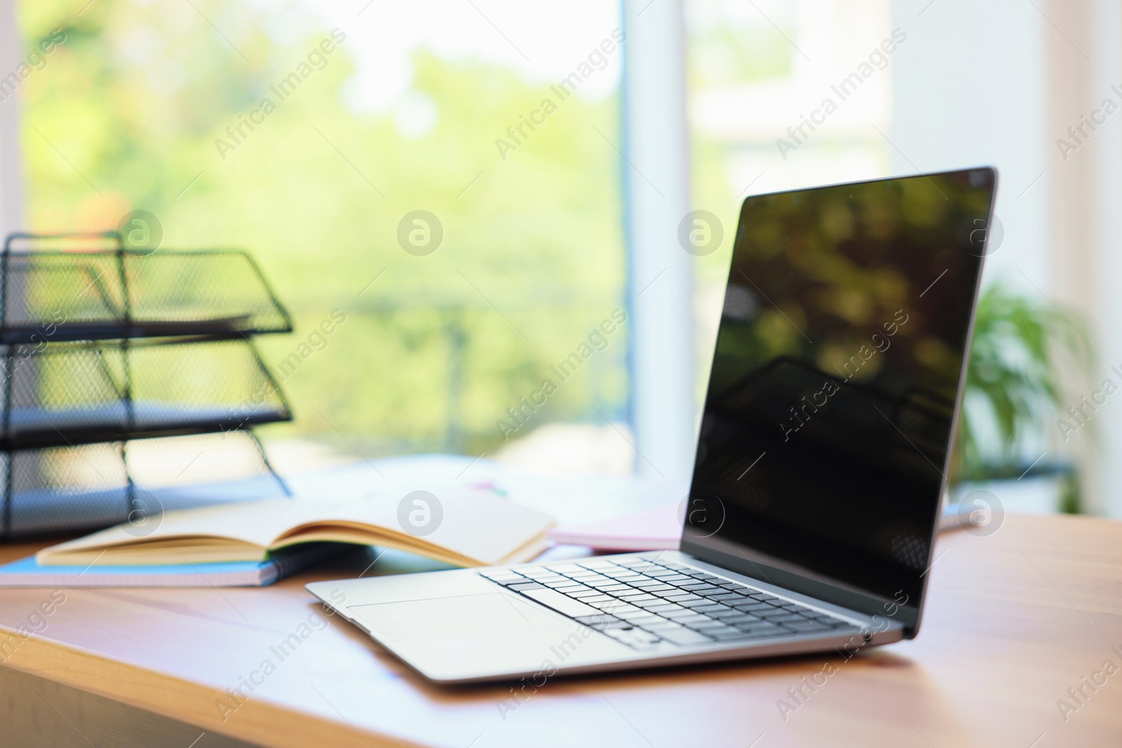 Photo of Home workspace. Modern laptop and stationery on wooden desk indoors