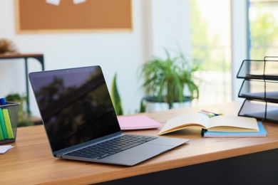 Photo of Home workspace. Modern laptop and stationery on wooden desk indoors