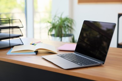 Photo of Home workspace. Modern laptop and stationery on wooden desk indoors