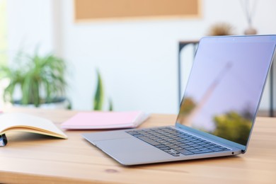 Photo of Home workspace. Modern laptop and stationery on wooden desk indoors, closeup