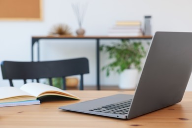 Photo of Home workspace. Modern laptop and stationery on wooden desk indoors, closeup