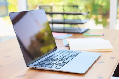 Photo of Home workspace. Modern laptop and stationery on wooden desk indoors