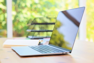 Photo of Home workspace. Modern laptop and stationery on wooden desk indoors
