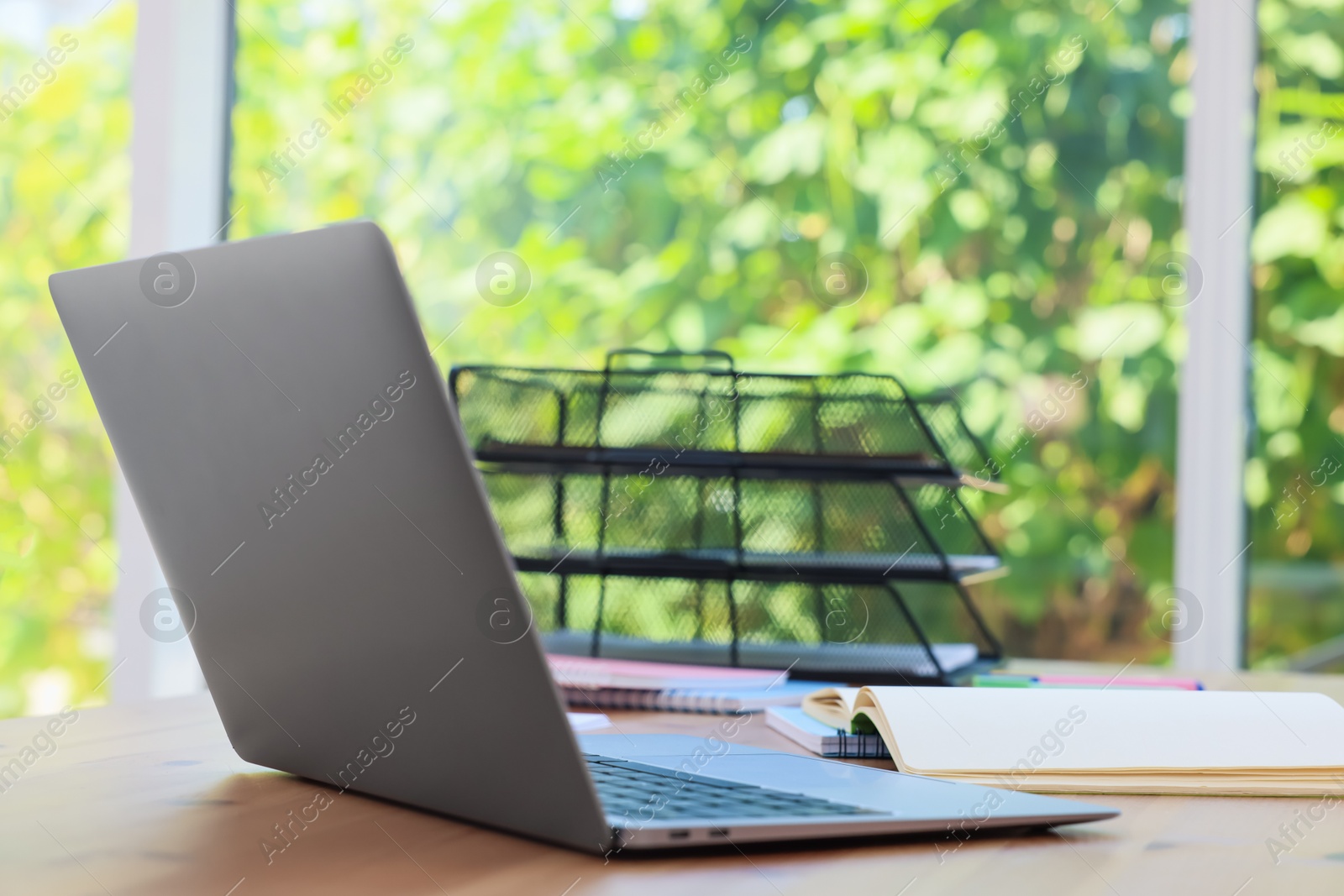 Photo of Home workspace. Modern laptop and stationery on wooden desk indoors