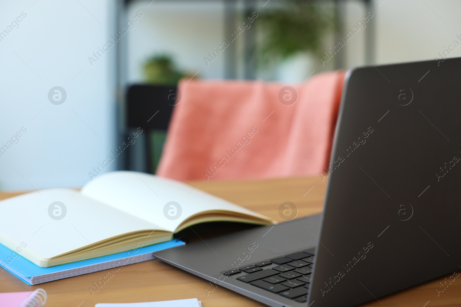 Photo of Home workspace. Modern laptop and stationery on wooden desk indoors, closeup