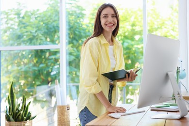 Photo of Woman using computer at wooden desk indoors. Home workplace