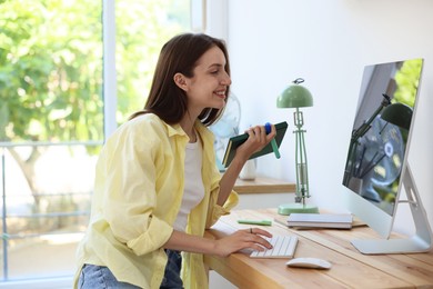 Photo of Woman using computer at wooden desk indoors. Home workplace